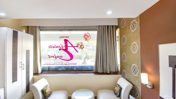 A hotel room with a large window, a sofa, a small round table, and a wardrobe. - Fabhotel Comfort 35 (Chandigarh)