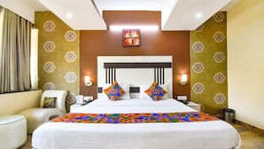 A hotel room with a large bed, two bedside tables, a chair, and a wall-mounted artwork. - Fabhotel Comfort 35 (Chandigarh)