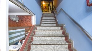 A staircase with granite steps and red accents, leading to a room with a wooden door and a fan. - Fabhotel Comfort 35 (Chandigarh)