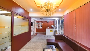 A hotel lobby with a reception desk, a chandelier, a seating area, and a wall with a clock. - Fabhotel Comfort 35 (Chandigarh)