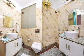 Un bagno con parete in marmo, un lavandino, un water e uno specchio.