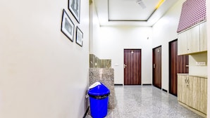 A hallway with a blue trash bin, a ceiling fan, and wooden doors. - Fabhotel The Castle Homestay (Jaipur)
