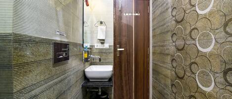 A modern bathroom with a wooden door, a white sink, and a towel rack.