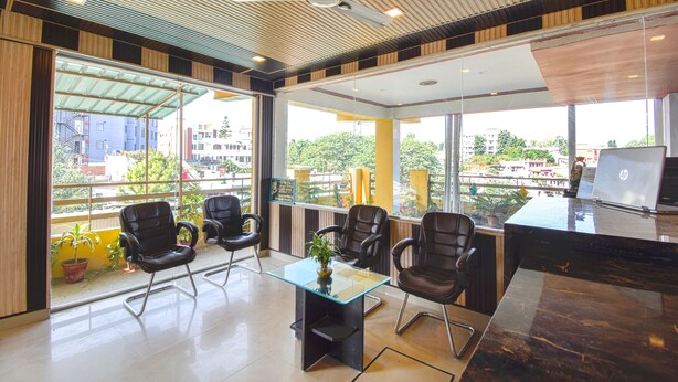 A modern office space with a glass table, black leather chairs, and a ceiling fan.
