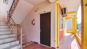 A staircase leading to a door, a fire extinguisher, and a balcony with yellow walls.