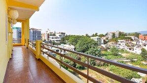 A balcony with a view of a residential area, including various buildings and greenery.