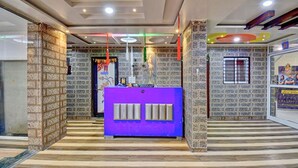 Un área de recepción con mostrador púrpura, paredes con diseño y suelo de baldosas.