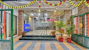 Vestíbulo de hotel con alfombra estampada, una escalera que sube al piso superior y elementos decorativos como flores y obras de arte en las paredes.