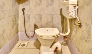 Casa de banho com sanita, bidé e mangueira de chuveiro.