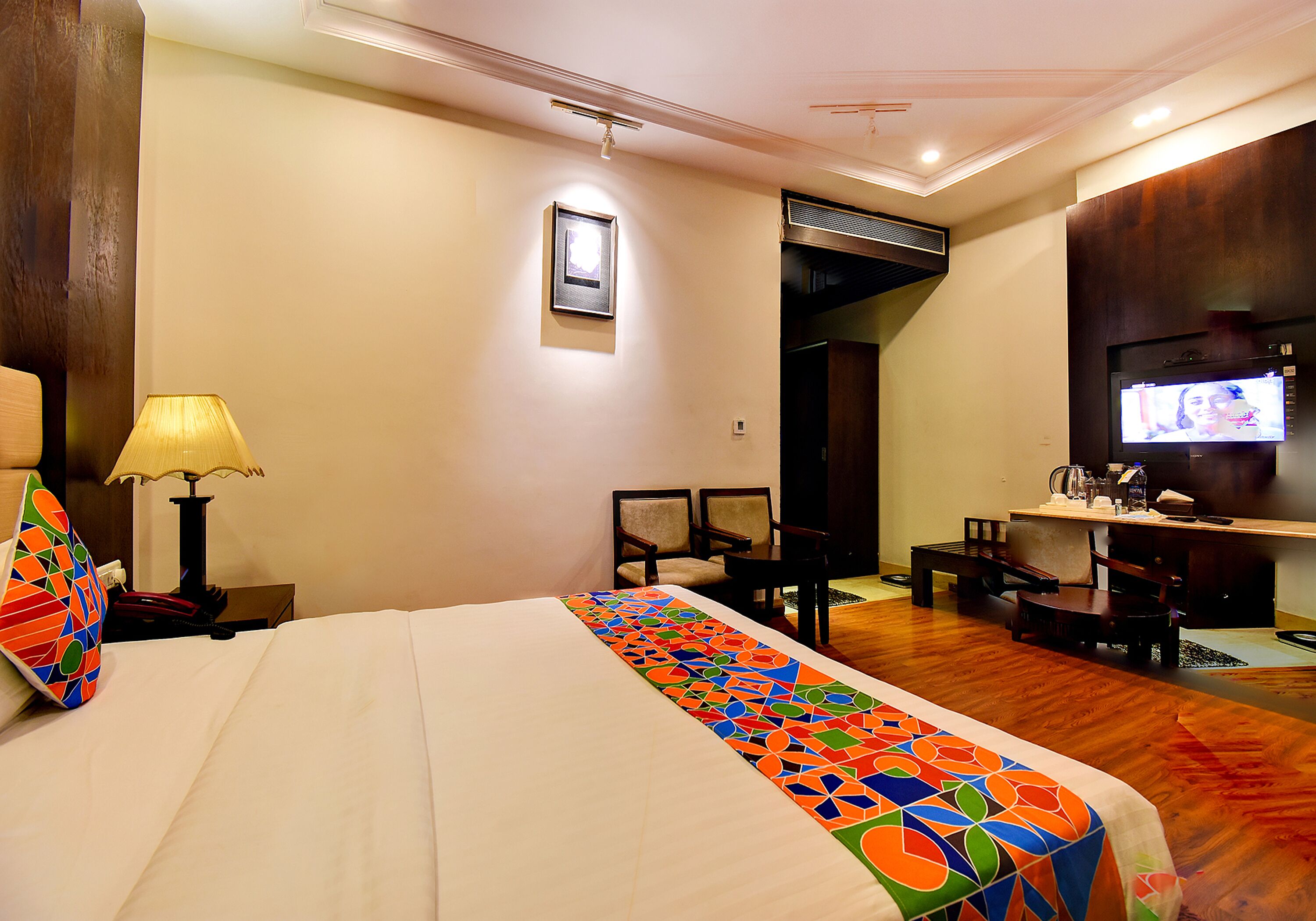 A hotel room with a large bed, a desk, a television, and a chair.