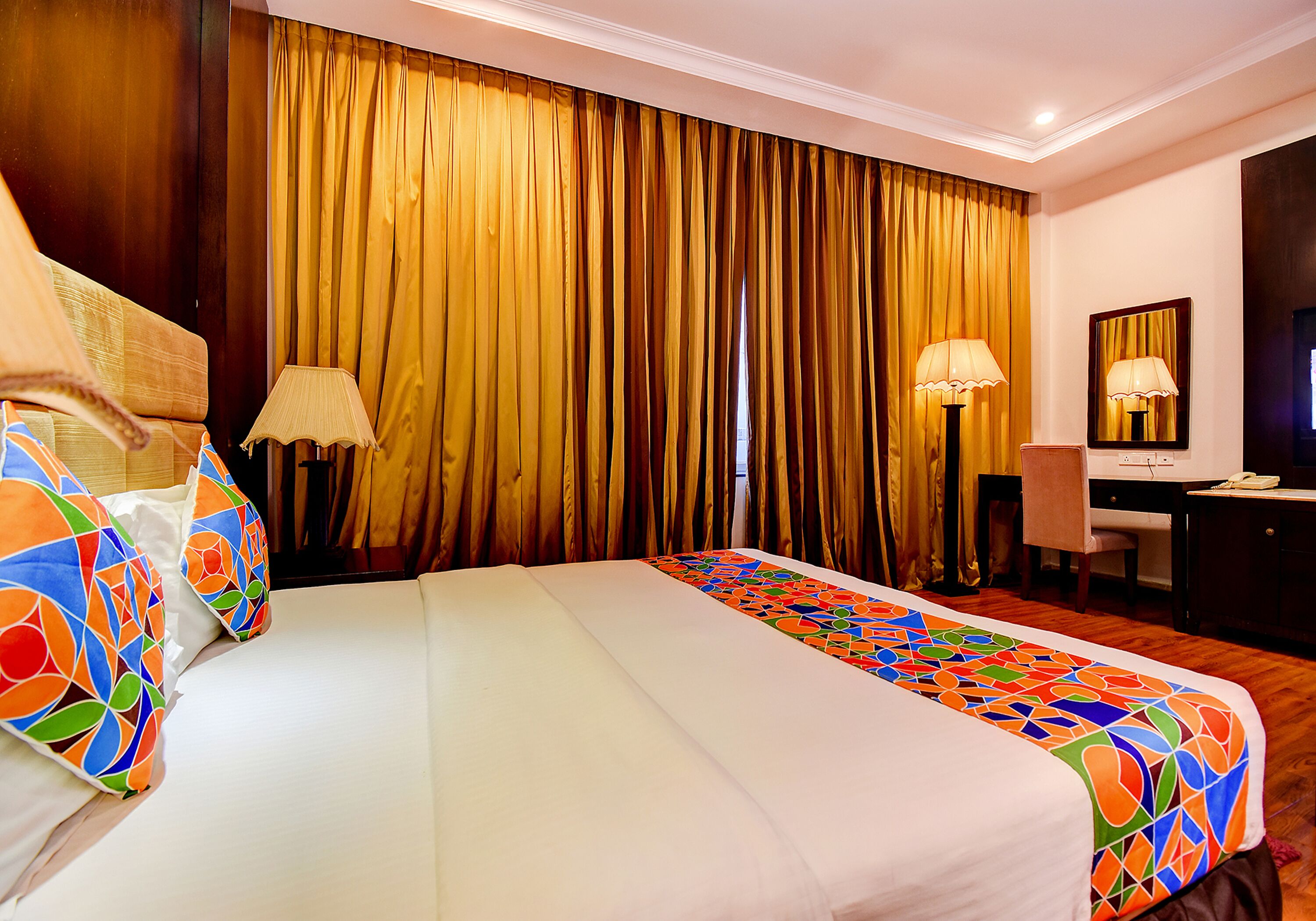 Une chambre d’hôtel avec un grand lit, deux lampes de chevet, un bureau et une chaise.