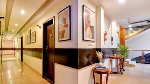 A hotel lobby with a long corridor, framed artwork on the walls, a reception desk, and a staircase. - Oriva Suvee Boutique (Bengaluru)