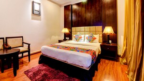A hotel room with a large bed, two bedside tables with lamps, a chair, a wooden floor, and a red rug. - Oriva Suvee Boutique (Bengaluru)