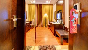 A hotel room with a wooden floor, a desk with a lamp, a television, and a 'Don't Disturb' sign. - Oriva Suvee Boutique (Bengaluru)