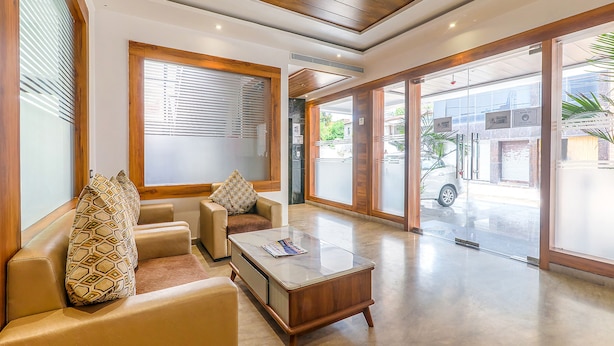 A spacious lobby with a seating area, a reception desk, and large glass doors leading outside. - Fabexpress Global Inn New (Lucknow)