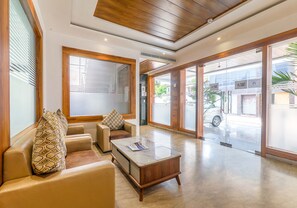 A spacious lobby with a seating area, a reception desk, and large glass doors leading outside. - Fabexpress Global Inn New (Lucknow)