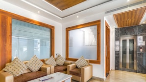 A lobby with a sofa set, a coffee table, and a reception desk. - Fabexpress Global Inn New (Lucknow)