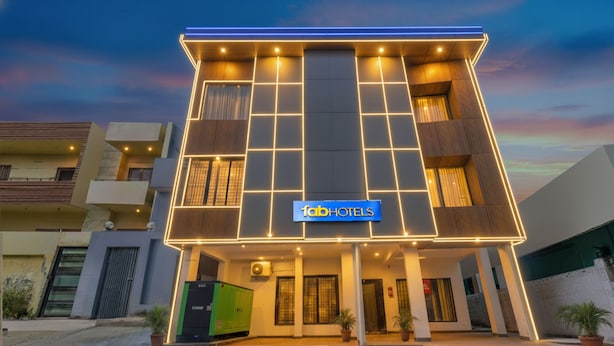 Un hotel moderno con un llamativo letrero de 'Tab Hotels', que presenta una fachada geométrica y líneas iluminadas.