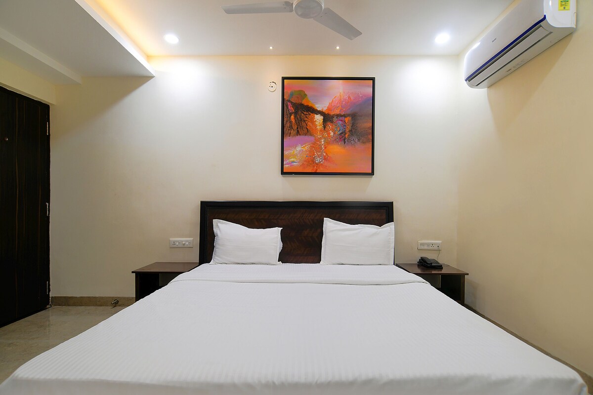 Habitación de hotel con una cama grande, ventilador de techo, aire acondicionado y un cuadro en la pared.