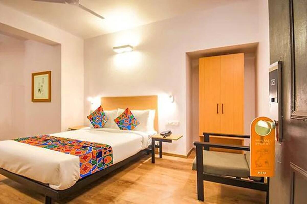 A hotel room with a bed, bedside table, lamp, and a wardrobe.