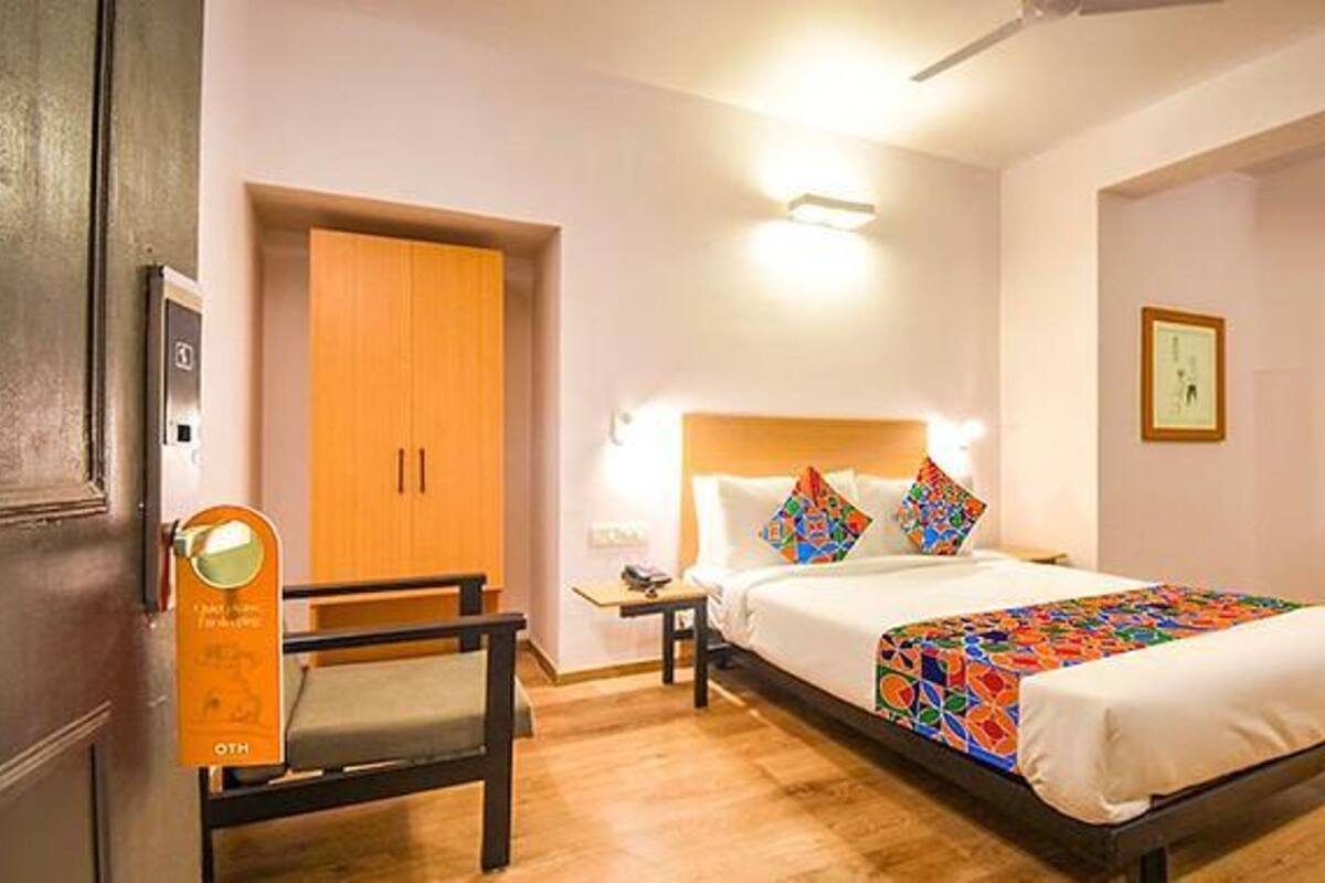 A hotel room with a bed, a desk, a chair, and a wardrobe.
