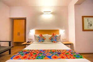 A hotel room with a bed, two nightstands, a wooden wardrobe, and a framed picture on the wall. - Via Heera Holiday Inn (Kolkata)