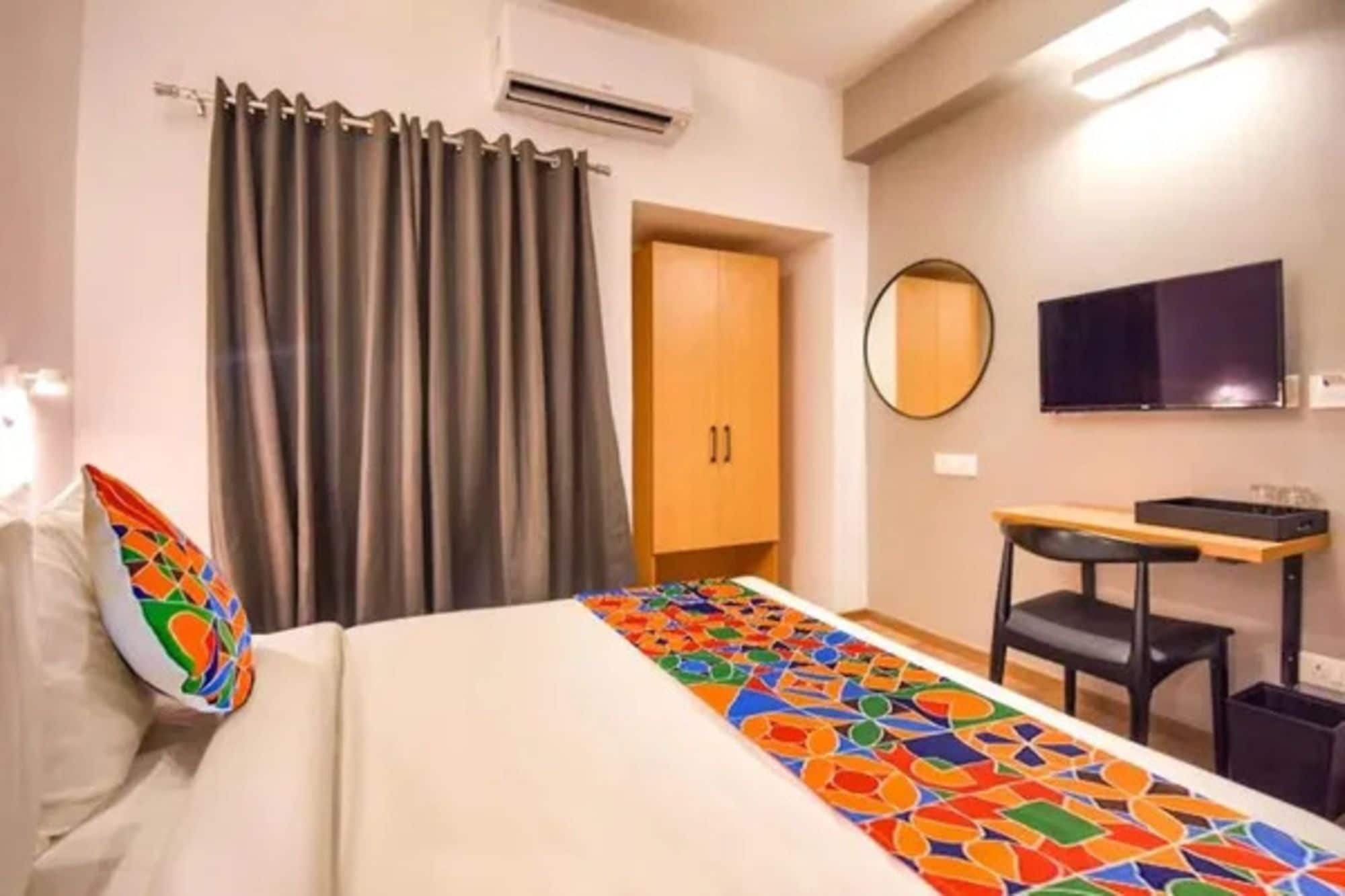 A hotel room with a bed, a desk, a chair, a TV, and a wardrobe.