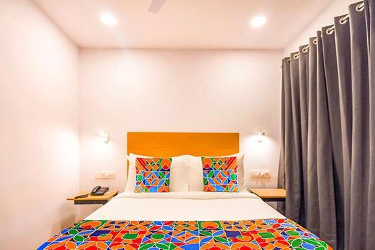 Habitació d'hotel amb llit, una petita taula de nit, un telèfon i cortines.