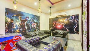 A modern living room with a sectional sofa, a glass coffee table, and two large wall murals. - FabHotel The Gayatri Palace (Lucknow)