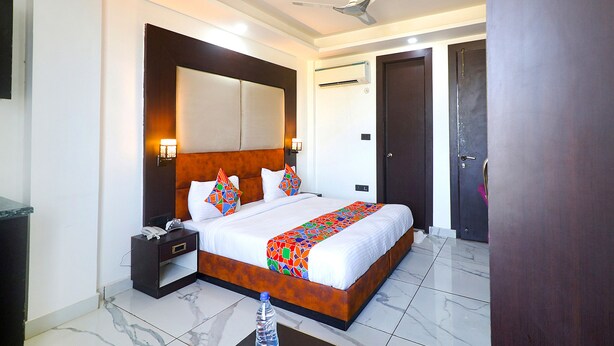 Una habitación de hotel con una cama grande, una mesita de noche, un ventilador de techo y una puerta.