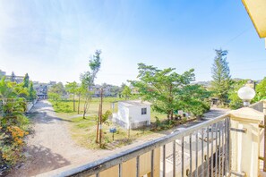A residential area with a white house, a dirt path, and a metal fence. - Fabhotel Shree Sai Residency (Mawal)