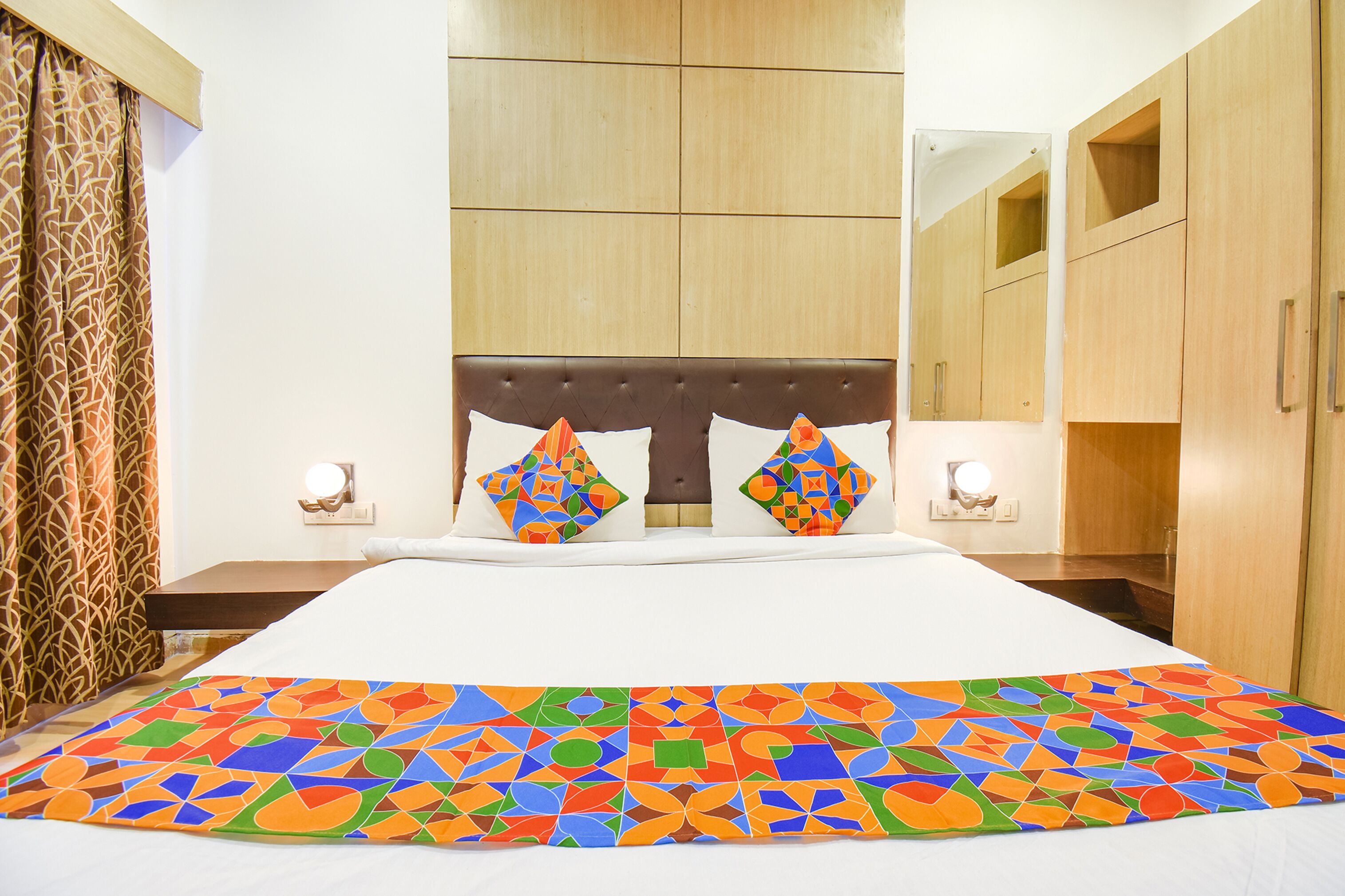 Een hotelkamer met een groot bed, een bedovertrek met patroon en houten meubels.