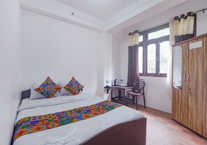 A bedroom with a bed, a desk, a chair, and a wardrobe. - Fabexpress Laxmi Niwas (Gangtok)