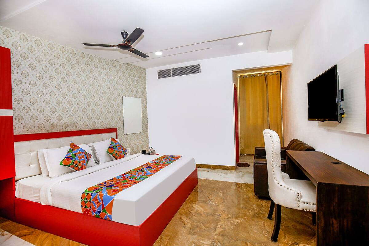 A hotel room with a bed, a desk, a chair, a television, and a ceiling fan.