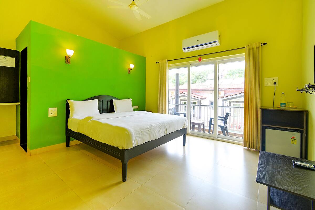 A bright room with a bed, a table, and a window with curtains.