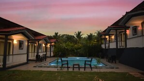 A pool area with two lounge chairs and a small table, surrounded by a covered patio with a railing. - FabHotel Vagator Retreat Resort With Swimming Pool - Nr. Chapora Fort (Vagator)