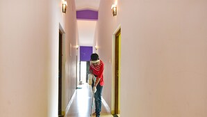 A person mopping a hallway with light-colored walls and a wooden floor. - FabHotel Vagator Retreat Resort With Swimming Pool - Nr. Chapora Fort (Vagator)