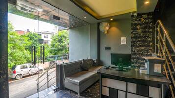 Een moderne hotel lobby met een bank, bureau, ventilator en een trap.