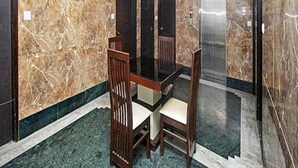 A conference room with a marble wall, a glass table, and wooden chairs. - Fabhotel Arihant Inn (New Delhi)