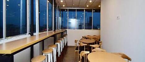 A conference room with a long table and chairs, large windows, and a view of the city at dusk.
