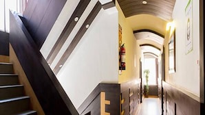Un couloir d’hôtel moderne avec un escalier, un comptoir d’accueil et un extincteur.
