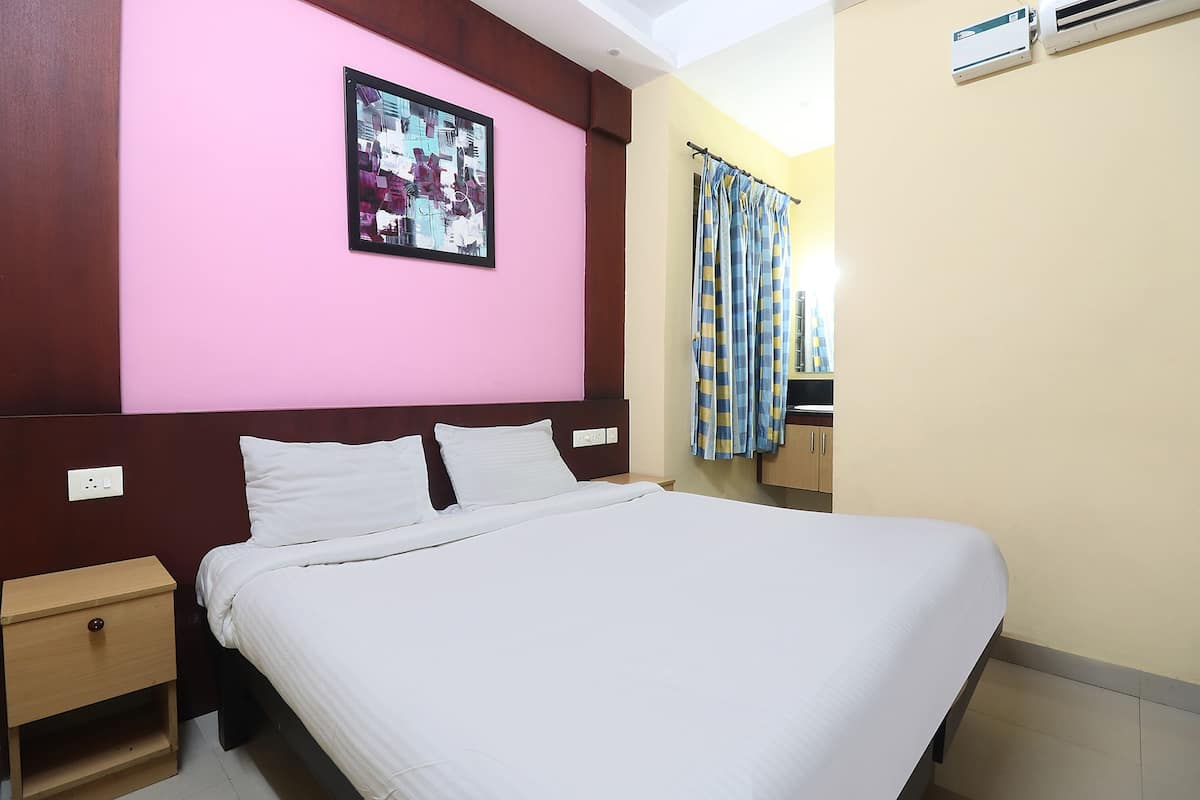 A hotel room with a large bed, a nightstand, a wall-mounted air conditioner, and a curtain.