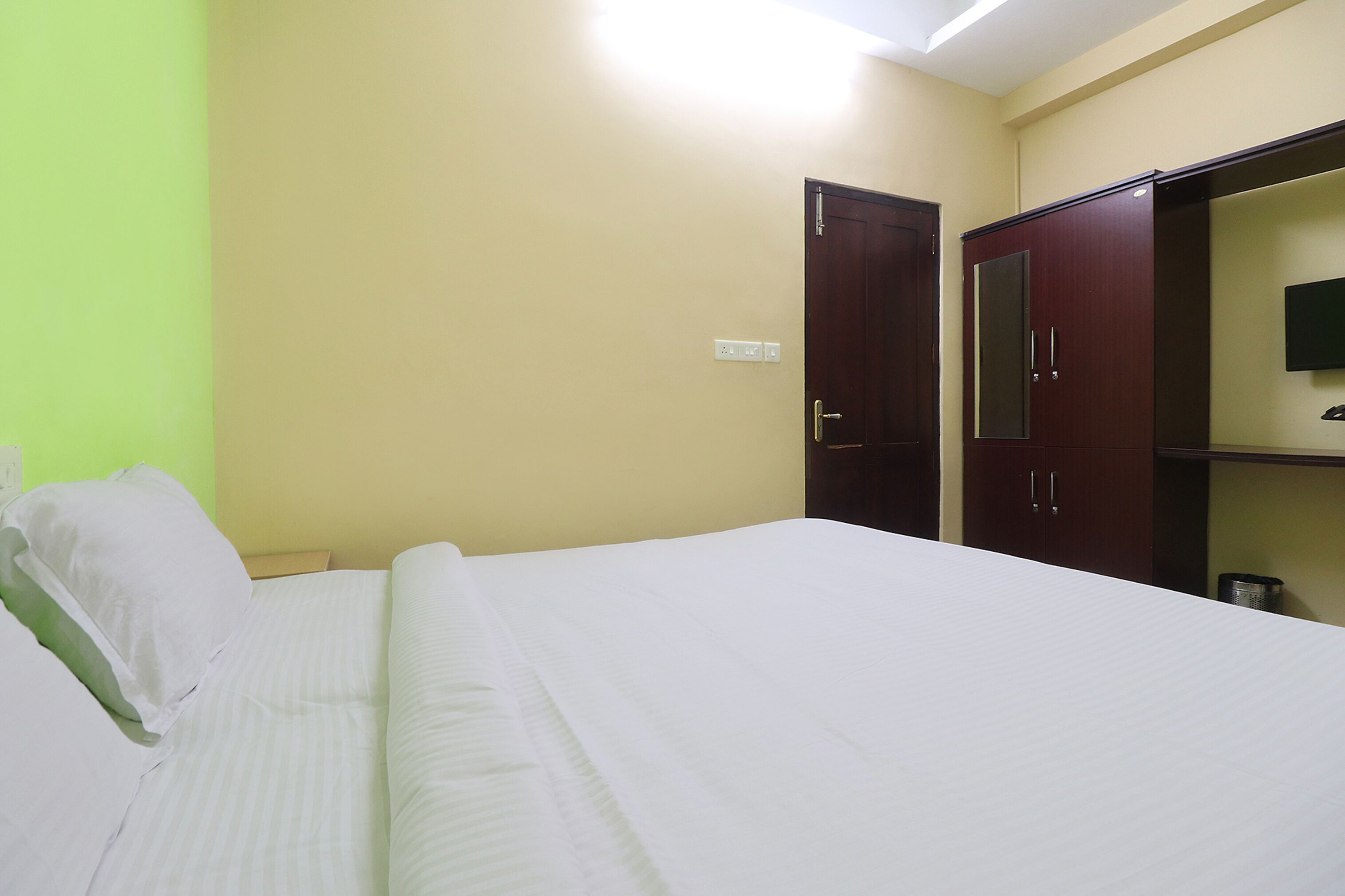 Een hotelkamer met een bed, kledingkast en een televisie aan de muur.
