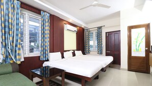 Una habitación de hotel con cama, sofá, mesa y cortinas.