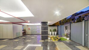 A modern lobby with a marble floor, lockers, potted plants, and a gated entrance. - Fabhotel Exotica (New Delhi)