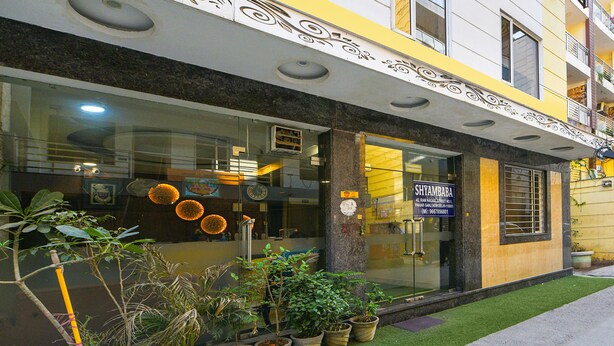 A building with a glass facade, potted plants, and a sign reading "SHYAMBABA." - FabHotel Baba Residency (New Delhi)