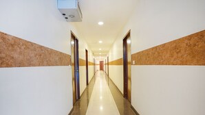 A long, well-lit hallway with doors on both sides, leading to a room at the end. - Fabhotel Shreyas Inn (Bengaluru)