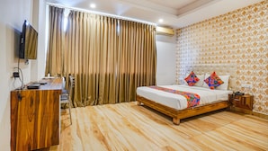 A bedroom with a wooden desk, a bed with colorful pillows, and a patterned wallpaper. - Fabhotel Shreyas Inn (Bengaluru)
