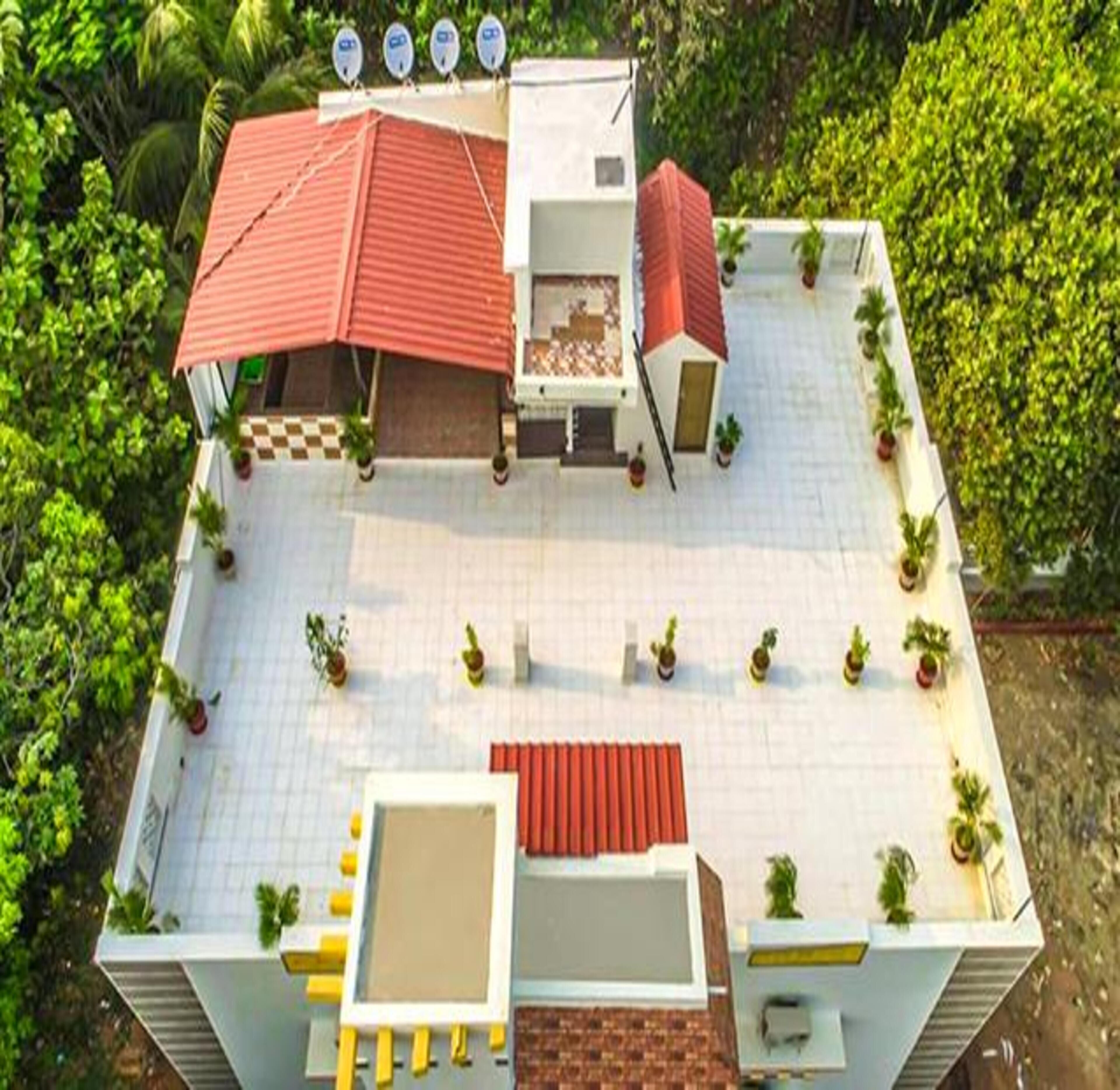 Eine Dachterrasse mit rotem Dach, mehreren Satellitenschüsseln und Topfpflanzen.
