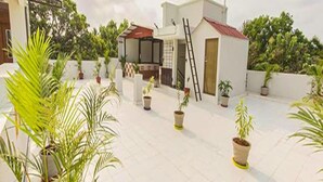 A rooftop terrace with potted plants, a small covered seating area, and a ladder. - Fabescape Queens Paradise (Vanur)